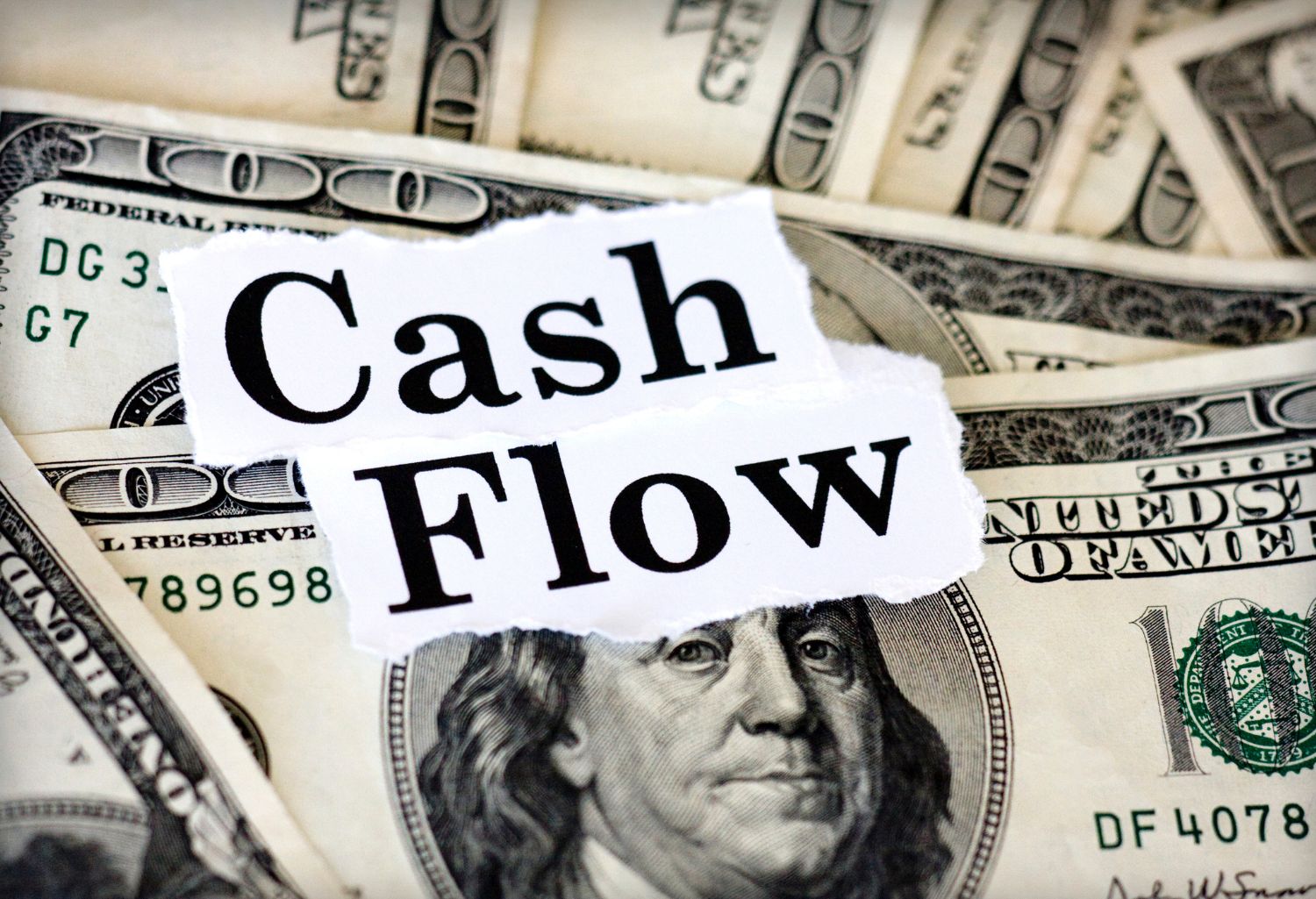 Cash Flow for Textile Distributors on a sheet of paper on top of hundred dollar bills